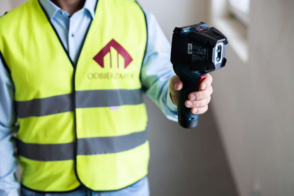 Ekspert ds. odbiorów mieszkań sprawdzający termoizolację kamerą termowizyjną.