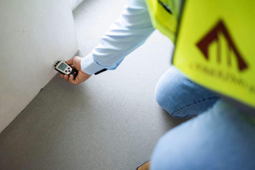 Ekspert ds. odbiorów mieszkań sprawdzający wilgotność ścian za pomocą wilgotnościomierza (higrometru). Profesjonalny nadzór budowlany i kontrola jakości wykonania nieruchomości.